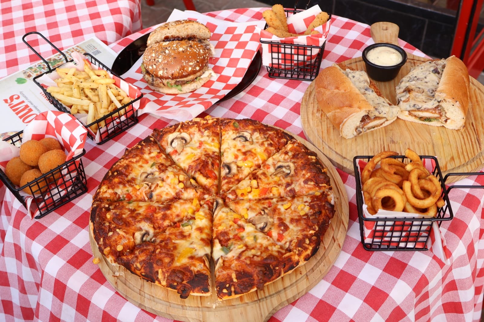 A spread of Jowi's pizza, burgers and sides
